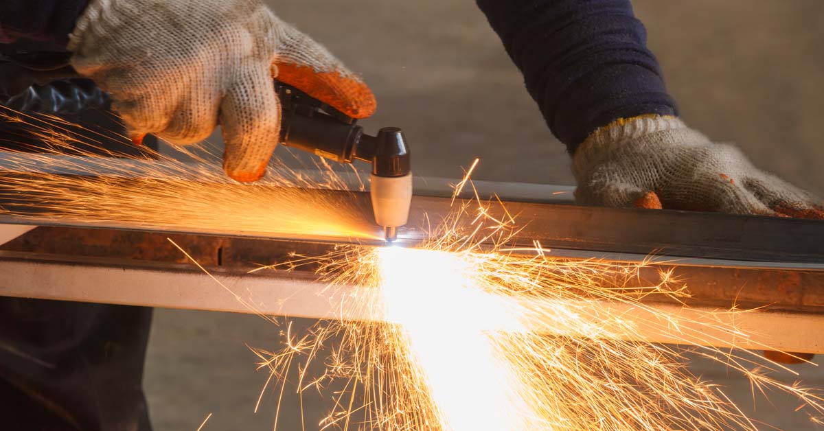 worker using plasma cutter to cut a piece of metal