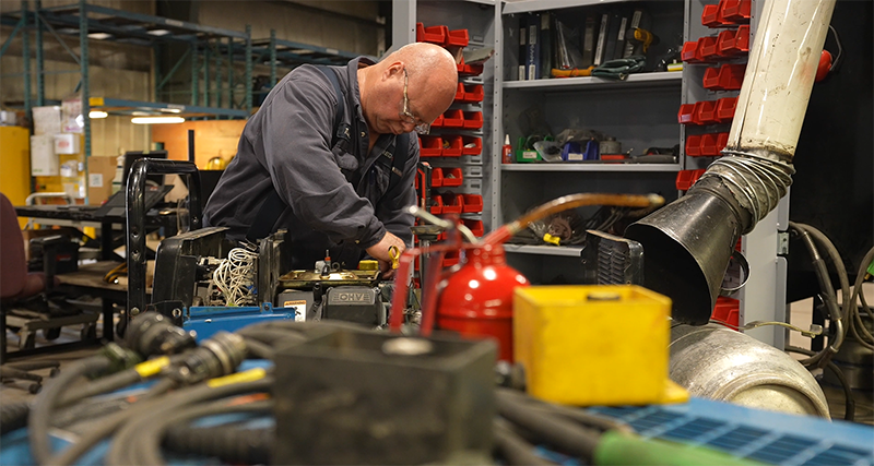 Technician servicing piece of equipment in shop